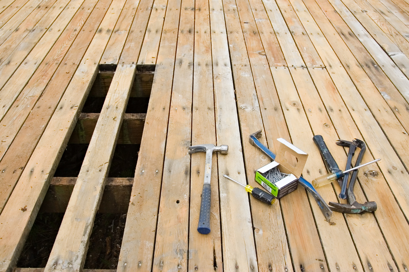 Wood deck undergoing repairs with replacement boards and carpentry tools.