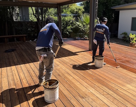 Contractors applying penetrating stain during a redwood deck refinishing project in Saratoga, CA