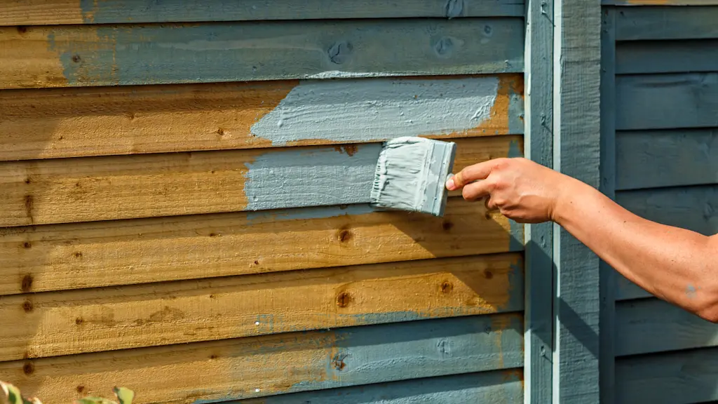 Exterior wood fence being painted with a brush for long-lasting protection and color.