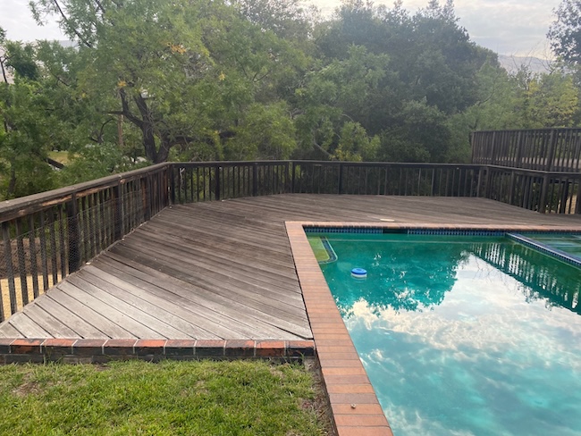 Weathered redwood pool deck before refinishing at a home in Fremont with faded wood and worn protective finish.