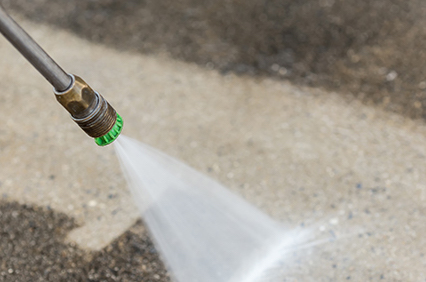 Pressure washer cleaning an exterior surface to remove dirt and mildew.