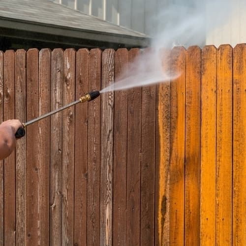 Pressure washing weathered wood fence before staining and sealing